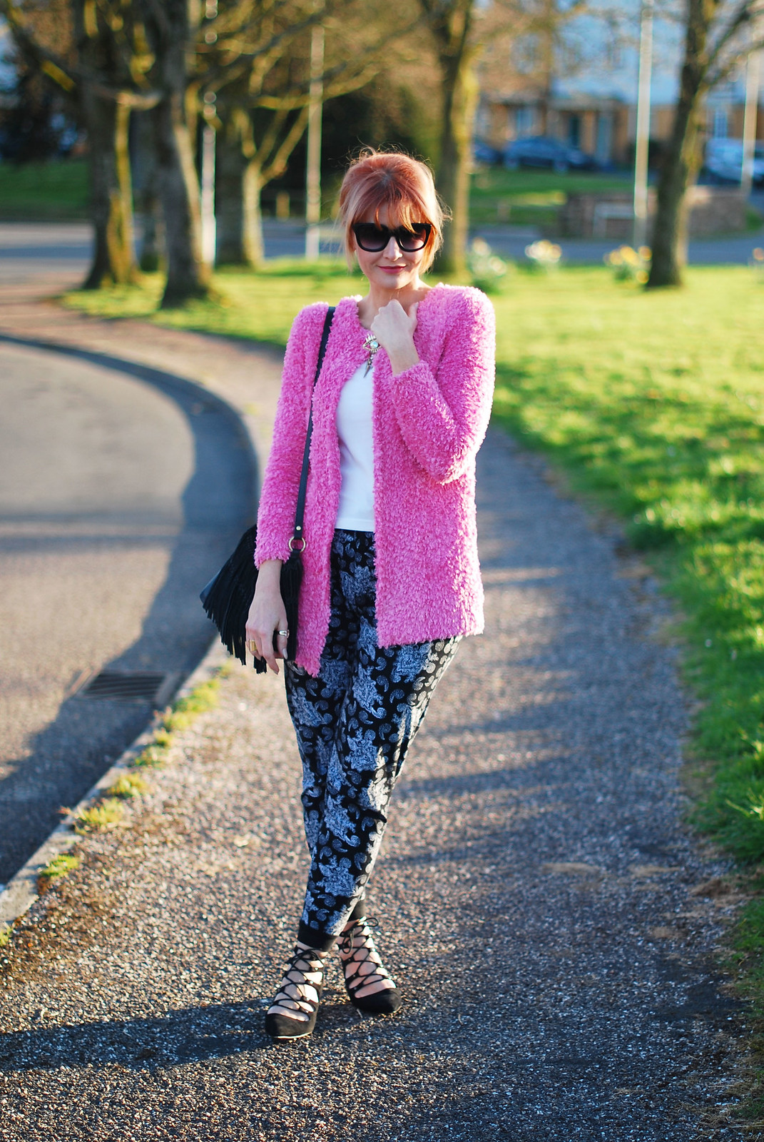 Spring style: Fluffy pink cardigan, paisley joggers, black lace up pointed flats, up do, cat eye sunglasses, evil eye brooch
