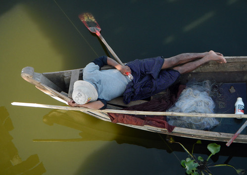 Napping after fishing in a boat by U Bein Bridge in Mandalay, Myanmar