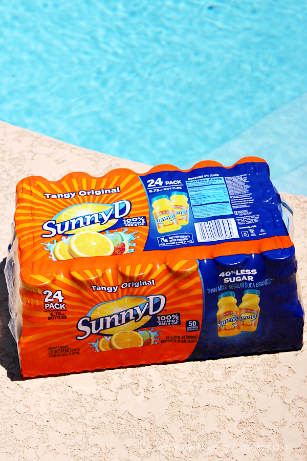 A case of sunny delight laying on a pool deck.