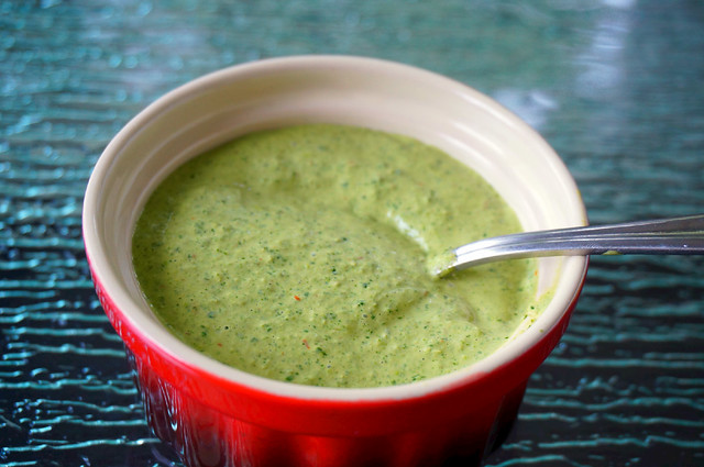 Closeup shot of pale-green cilantro sauce in a bright red ramekin