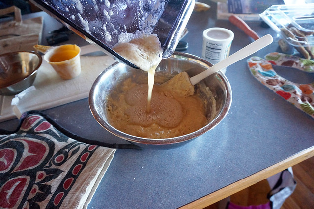 Pouring browned butter into cornbread batter, in the midst of a counter littered with books, a hotpad with a Northwestern Indian pattern, a baby bib, and other vacation house sundries