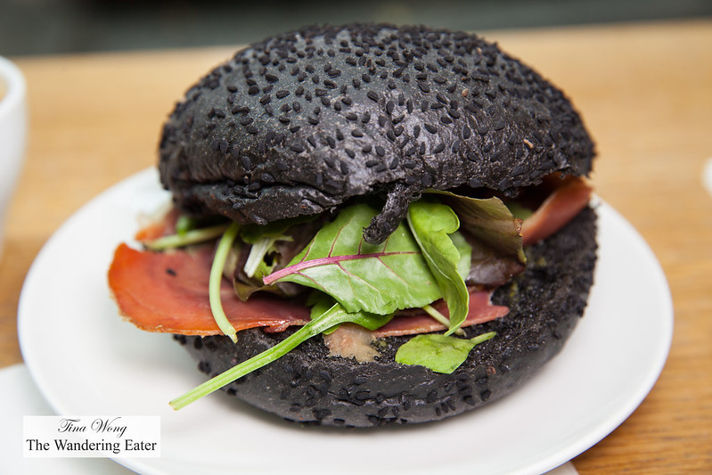 Squid ink roll with sesame seeds filled with thinly sliced ham and mesculun mix