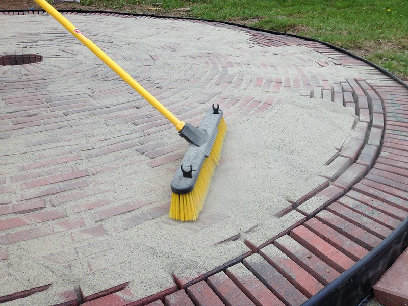 Spreading sand in cracks on firepit patio bricks